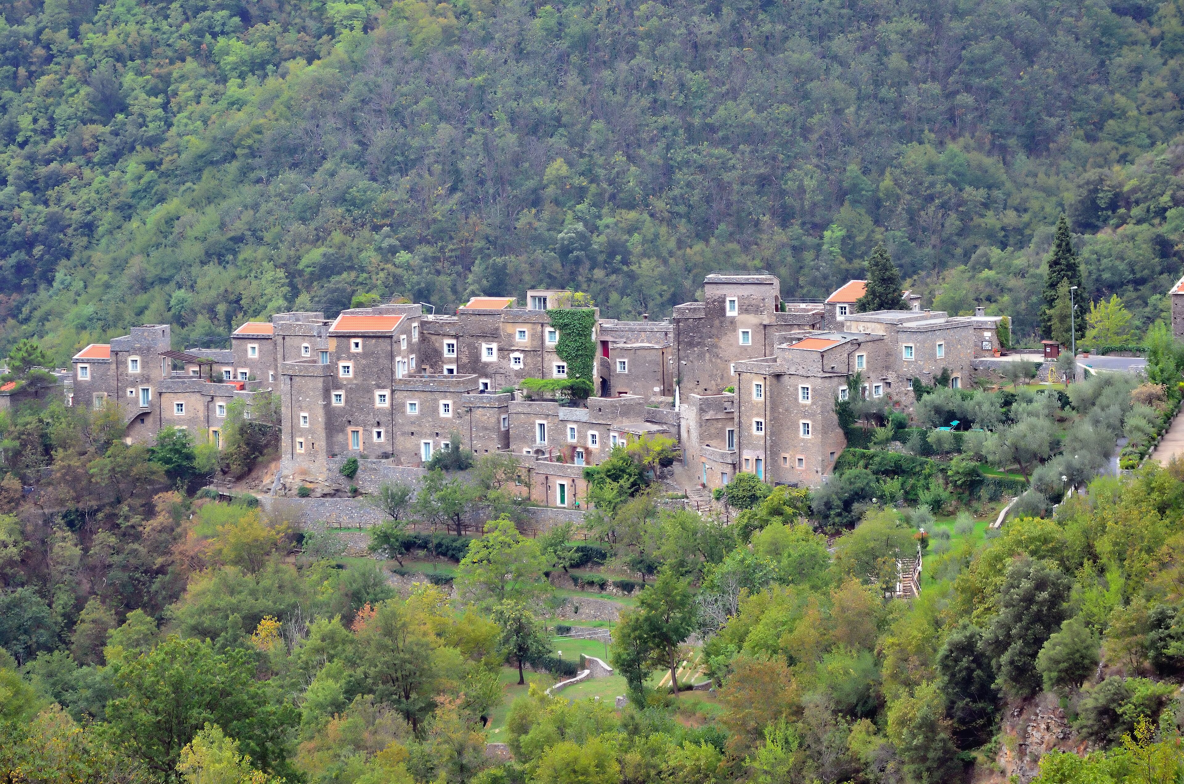 A hillside village with traditional stone buildings and lush greenery.
