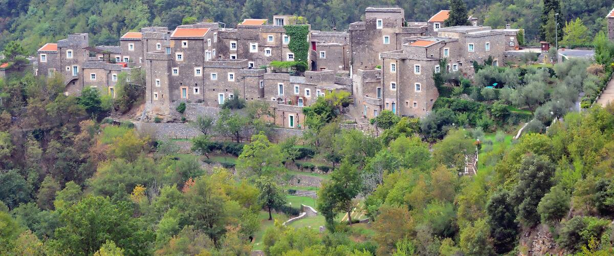 A hillside village with traditional stone buildings and lush greenery.