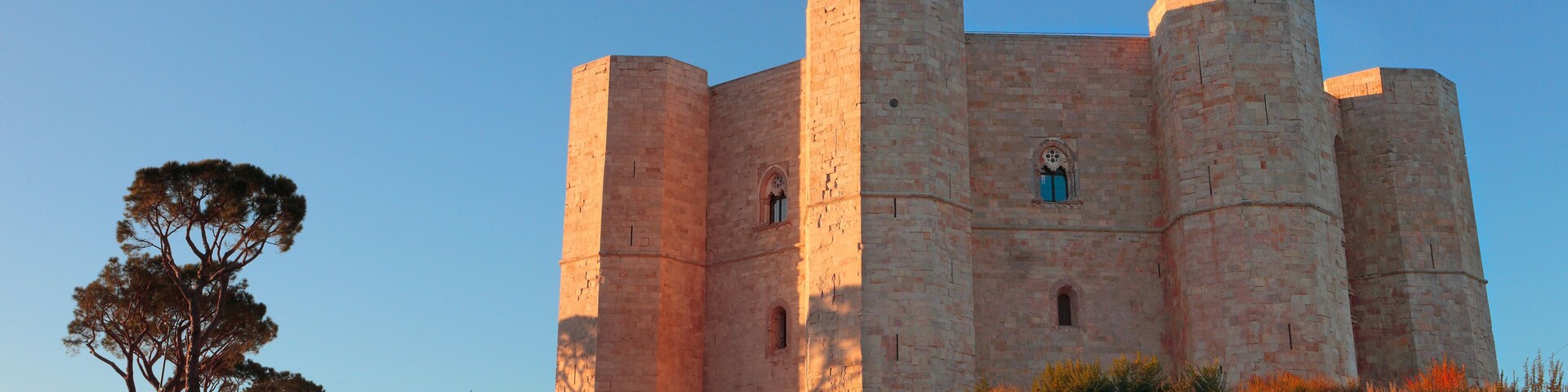 Un castillo medieval grande con cuatro torres y una entrada central.