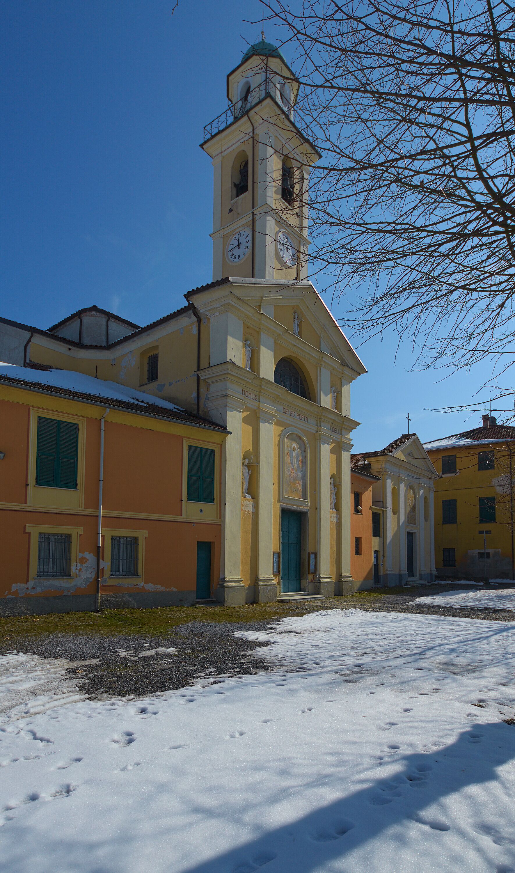 A snow-covered church with a bell tower and a statue in front.