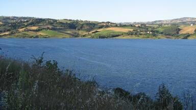 A lake with surrounding hills and scattered houses.