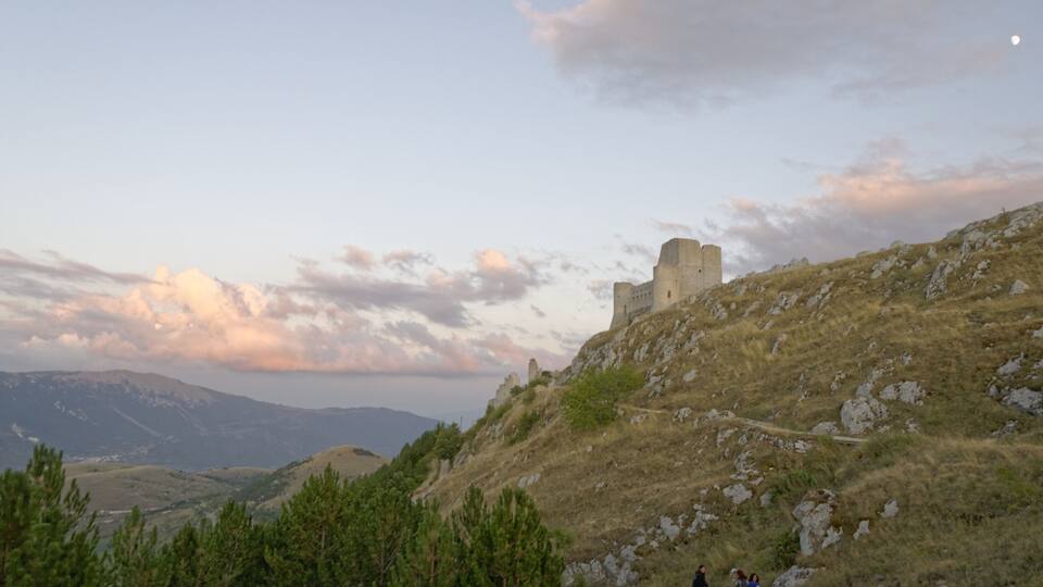 A castle on a hill with a clear sky and distant mountains.