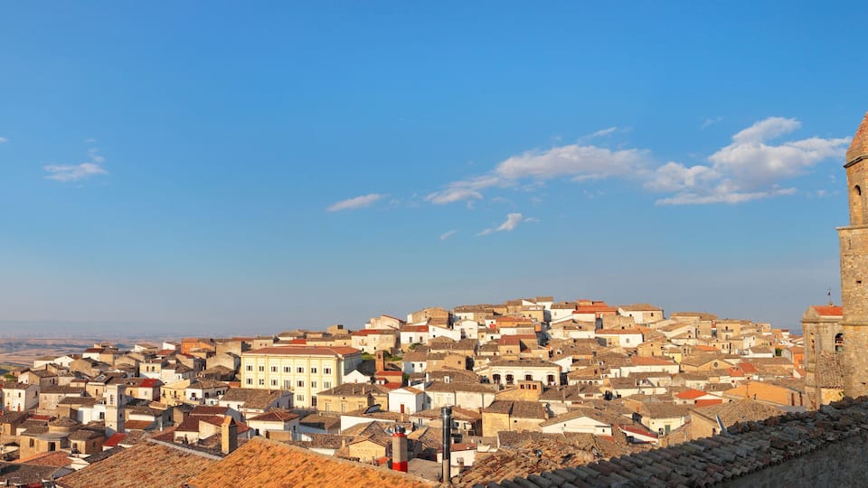 A historic town with a prominent tower and a stone wall.
