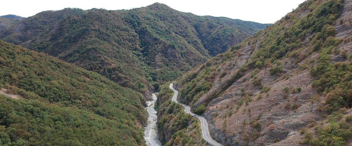 A winding road through a valley with dense forested hills.