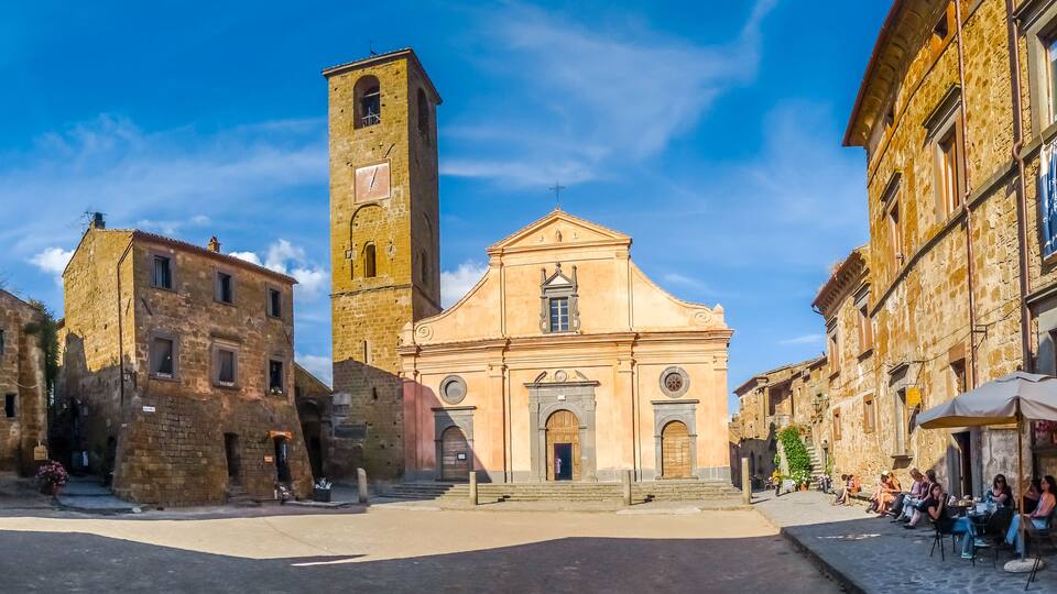 A historic town square with a church, a bell tower, and stone buildings.