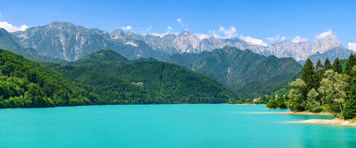 A turquoise lake surrounded by green mountains and dense forests.