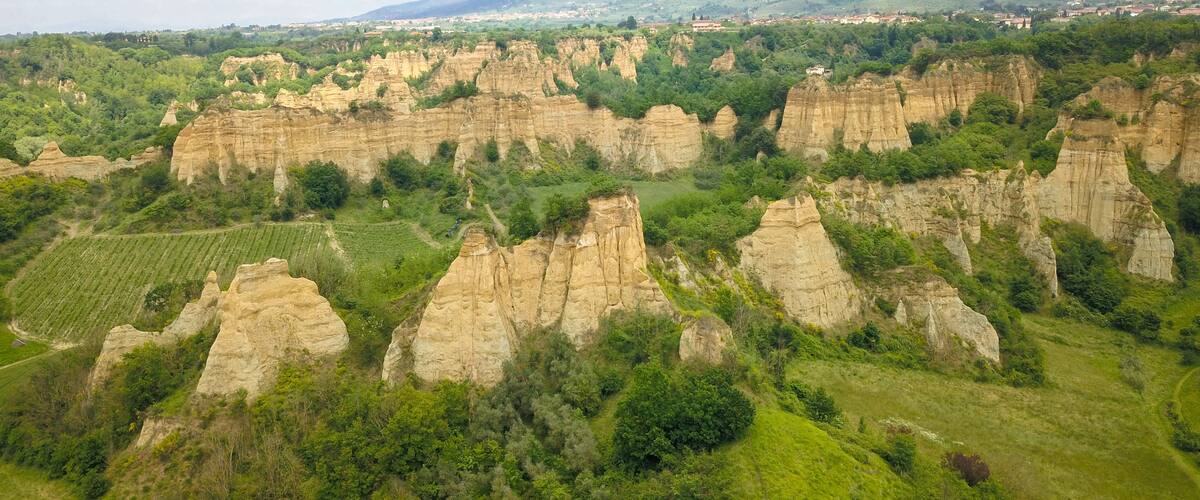 A landscape with rugged, eroded rock formations and a distant town.