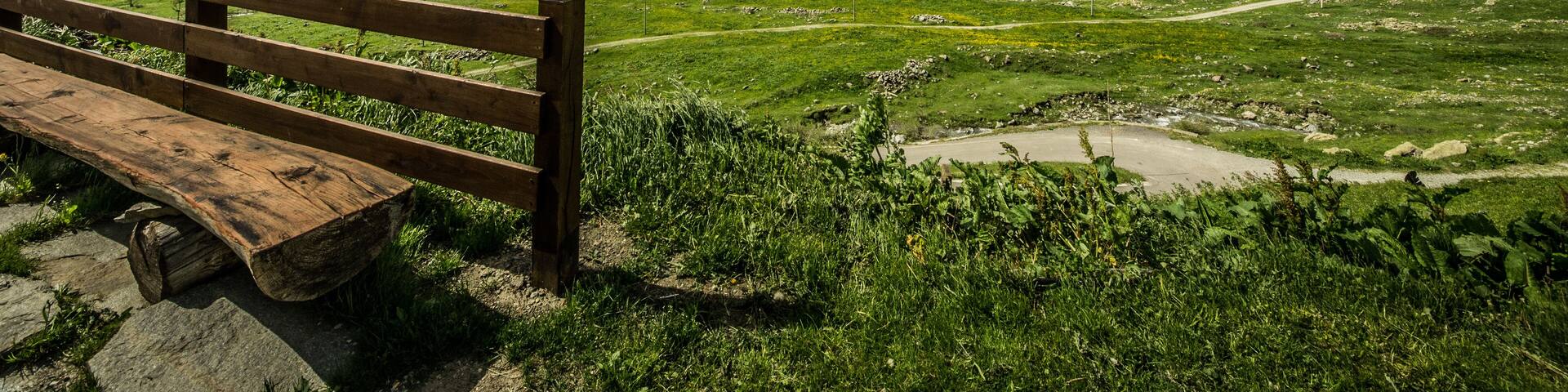 A wooden bench overlooking a mountainous landscape with a clear sky.
