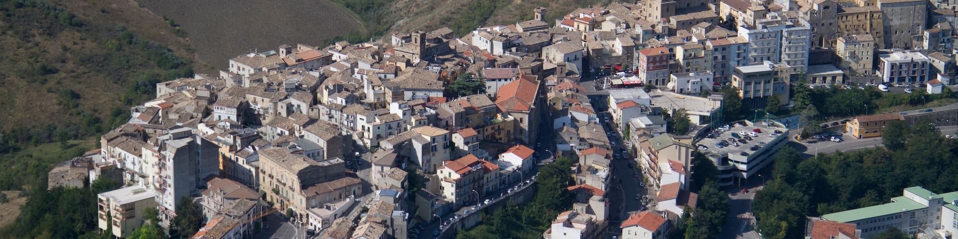 Vista aérea de un pueblo histórico con una iglesia central, calles serpenteantes y colinas circundantes.