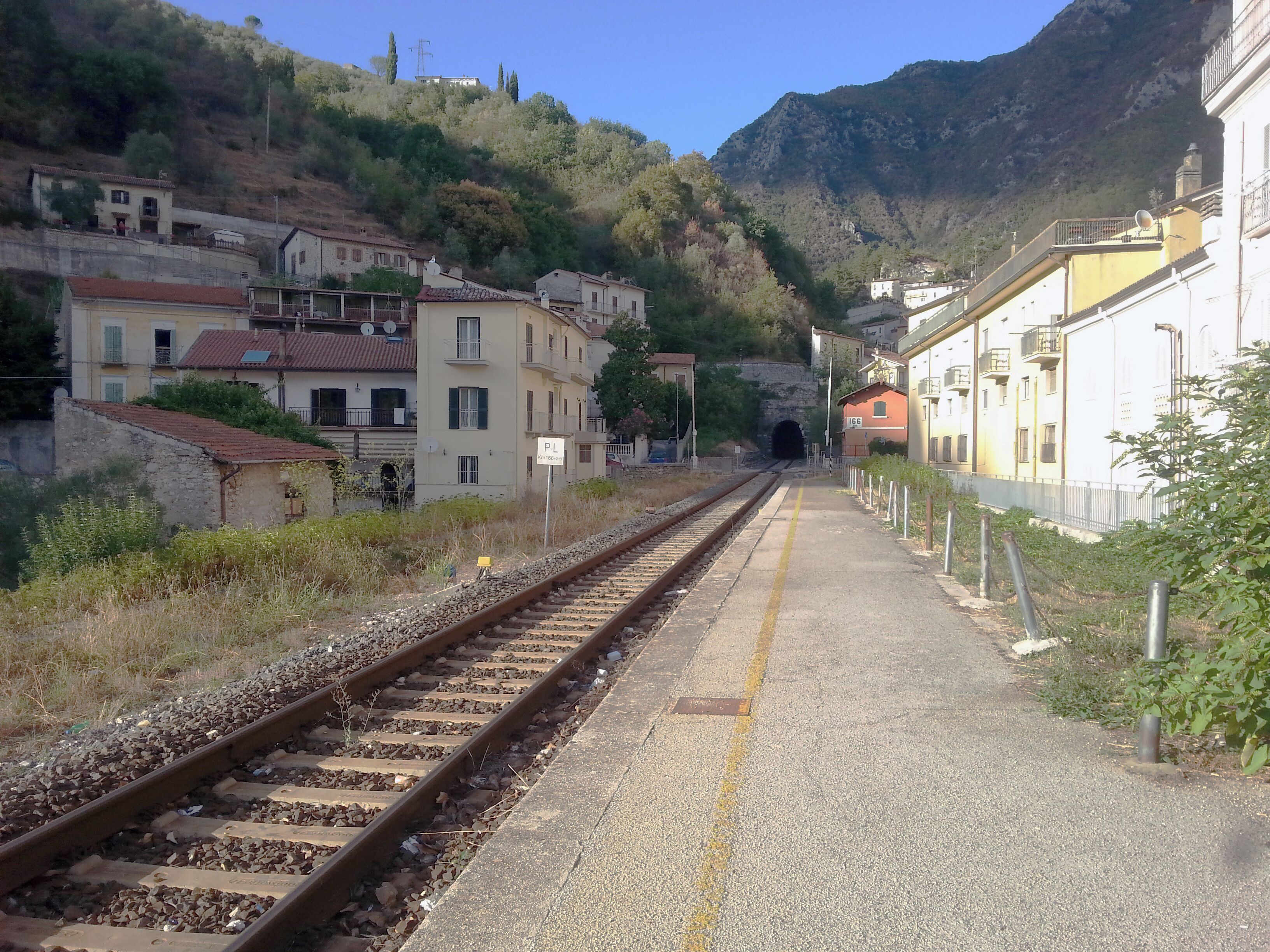 Antrodoco Centro railway stop (province of Rieti, central Italy), on the Terni-Rieti-L'Aquila-Sulmona line. View of the tracks heading to L'Aquila with the level crossing and the portal of the Castello rail tunnel.