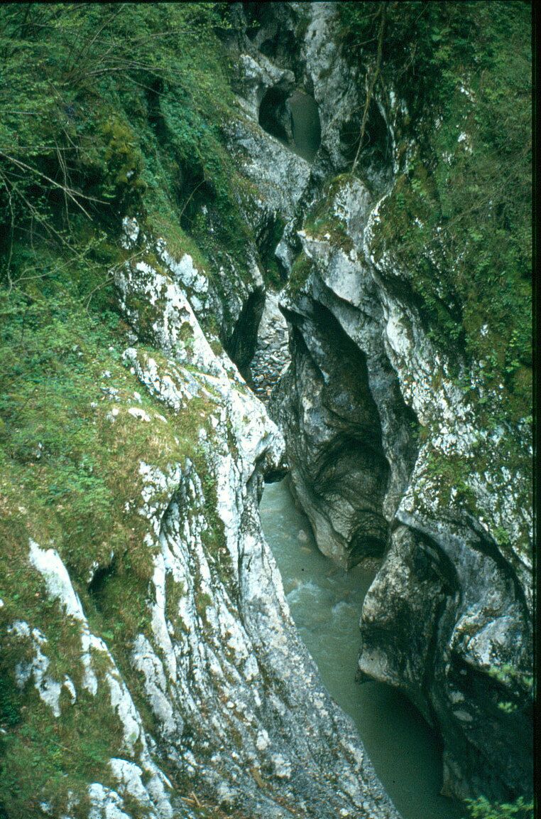 A narrow, rocky waterway surrounded by moss-covered cliffs.