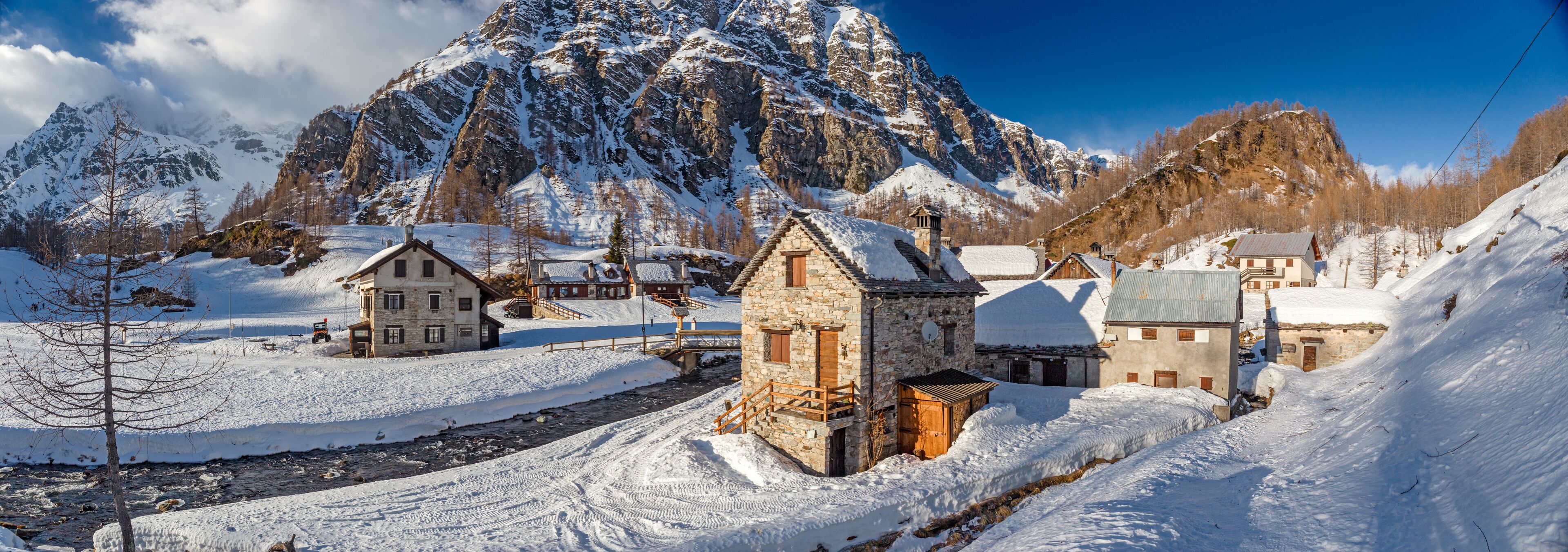 Panoramic view of the sunny snow-covered landscape of the village of Crampiolo, above the Alpe Devero in Piedmont, Italy.