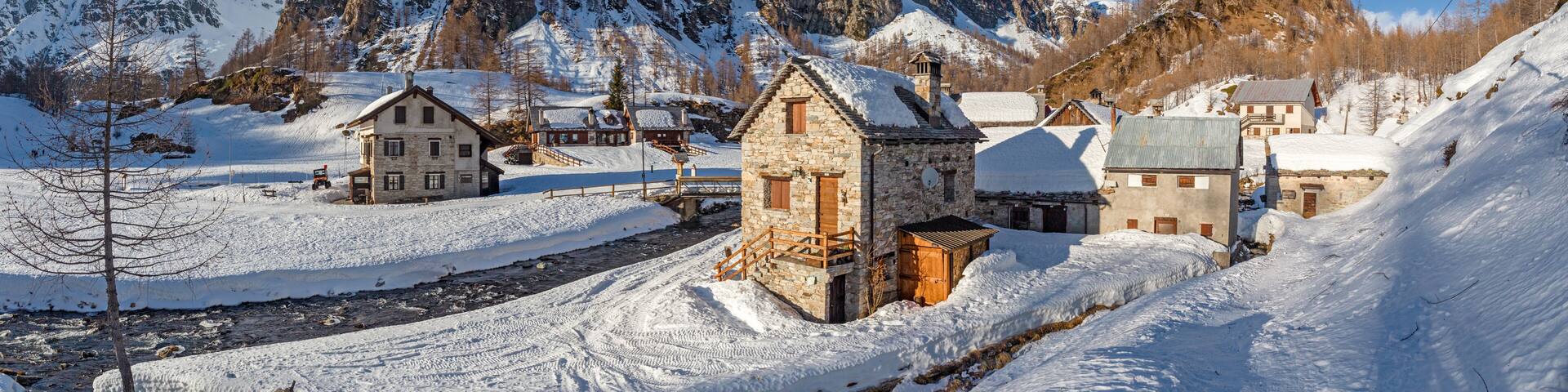 A snow-covered village with stone buildings and a mountain in the background.