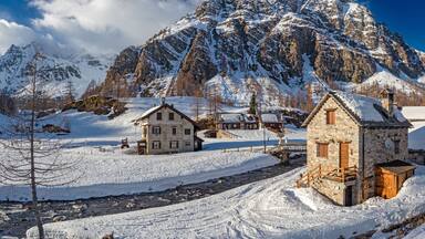 Un pueblo cubierto de nieve con edificios de piedra y una montaña al fondo.