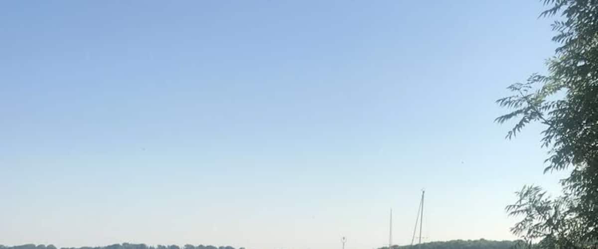 A calm lake with boats, grassy banks, and a clear sky.