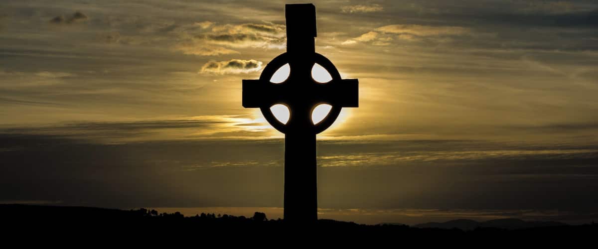 A cross silhouetted against a sunset sky.
