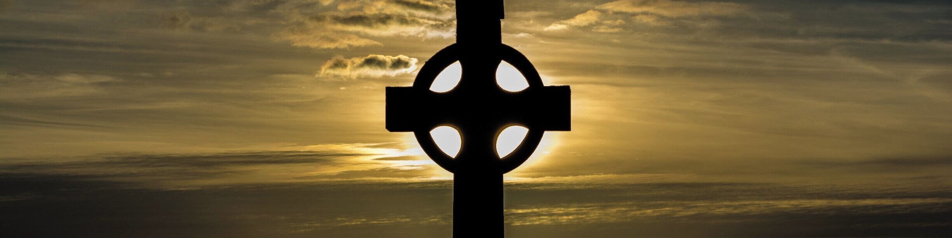 A cross silhouetted against a sunset sky.