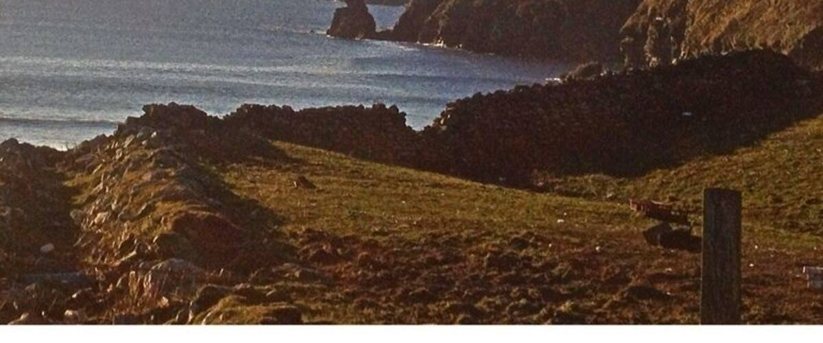 A coastal landscape with rocky terrain and a clear sky.