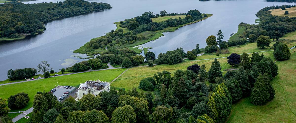 A large lake surrounded by lush greenery and a historic building.