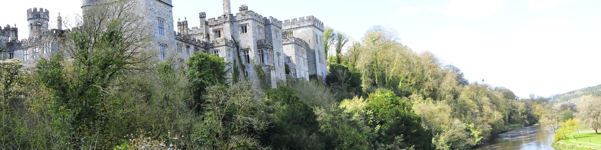 Un castillo a orillas de un río, rodeado de vegetación.