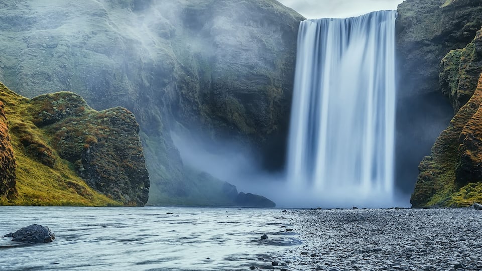A waterfall cascading down a rocky cliff into a calm body of water.