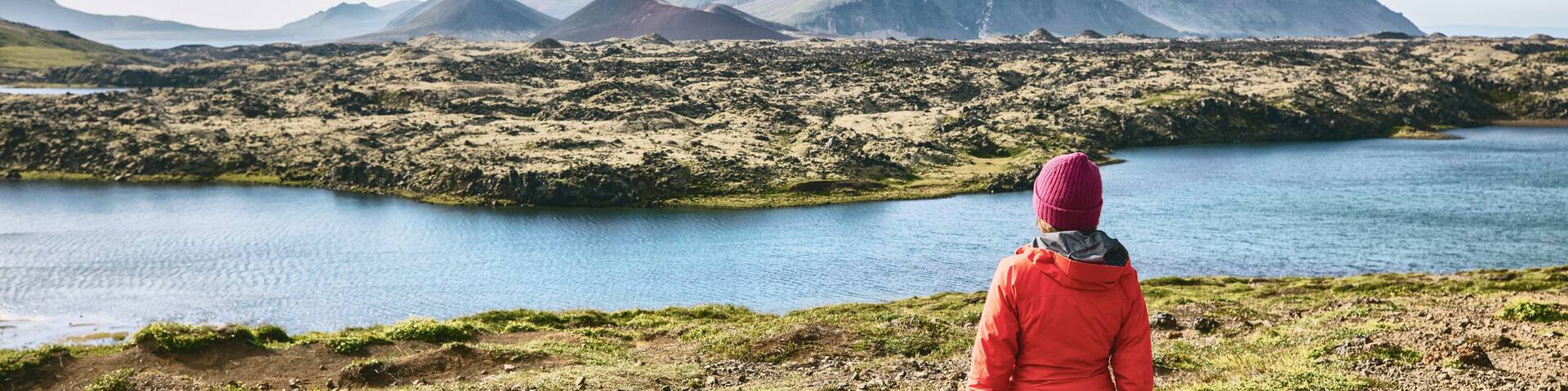 Iceland hiking travel adventure - woman tourist walking in mountain landscape looking at amazing view of nature, panorama banner.