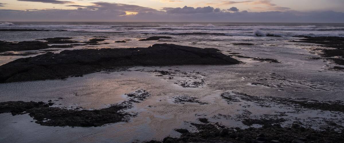 A rocky shoreline with waves at sunset.