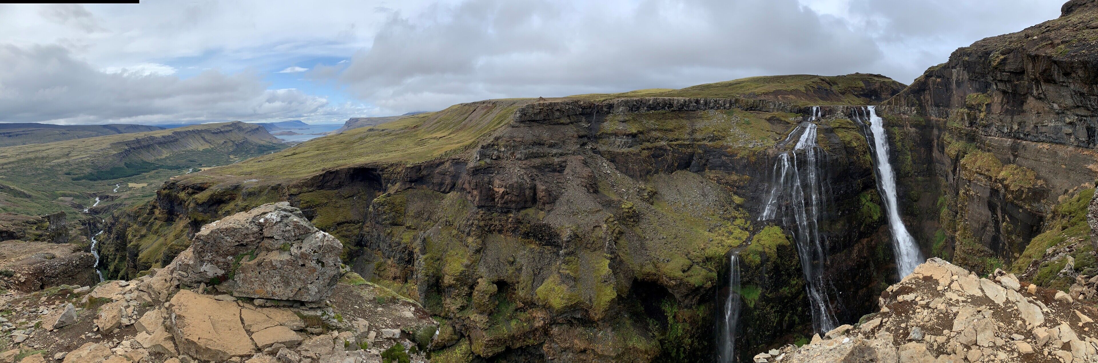 A mountainous landscape with a waterfall cascading down a rocky cliff.