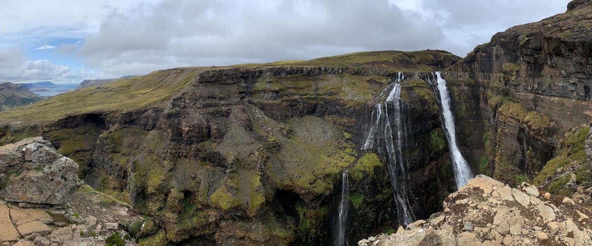 A mountainous landscape with a waterfall cascading down a rocky cliff.