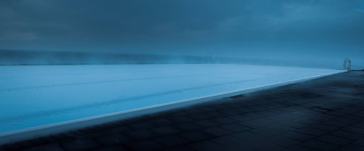 A calm, reflective pool with a dark, cloudy sky.