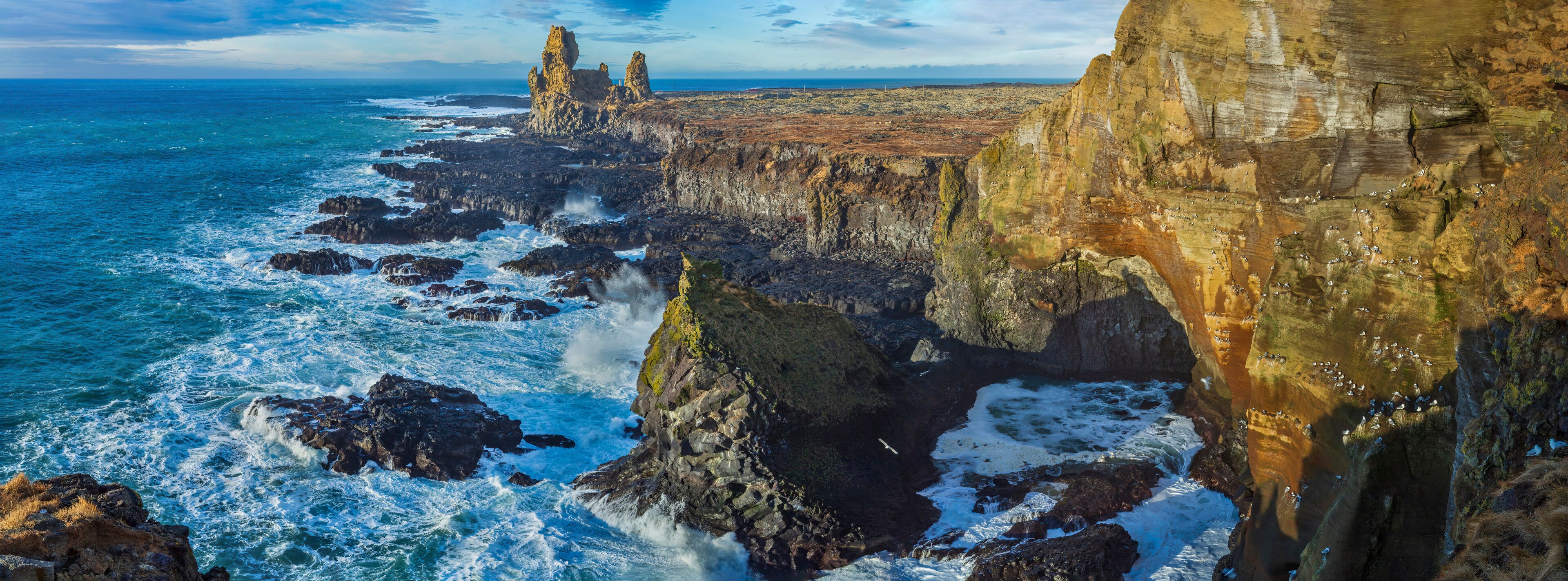 A rugged coastline with towering cliffs and a turbulent sea.