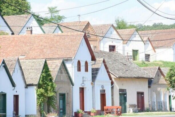 A row of white houses with steep roofs and green shutters.