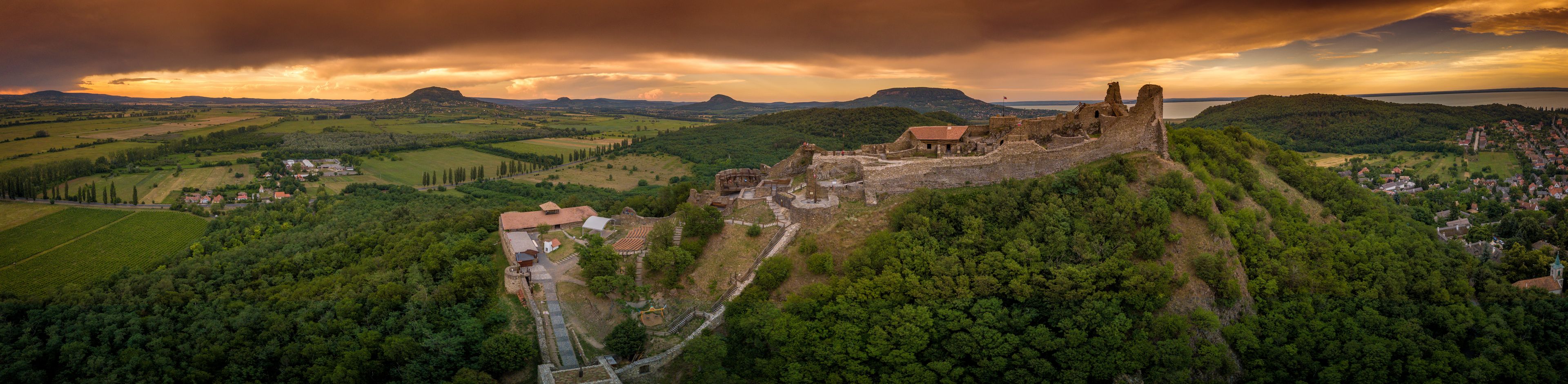 Aerial sunset panorama of ruined medieval Szigliget castle in Hungary above the Lake Balaton with orange yellow sky