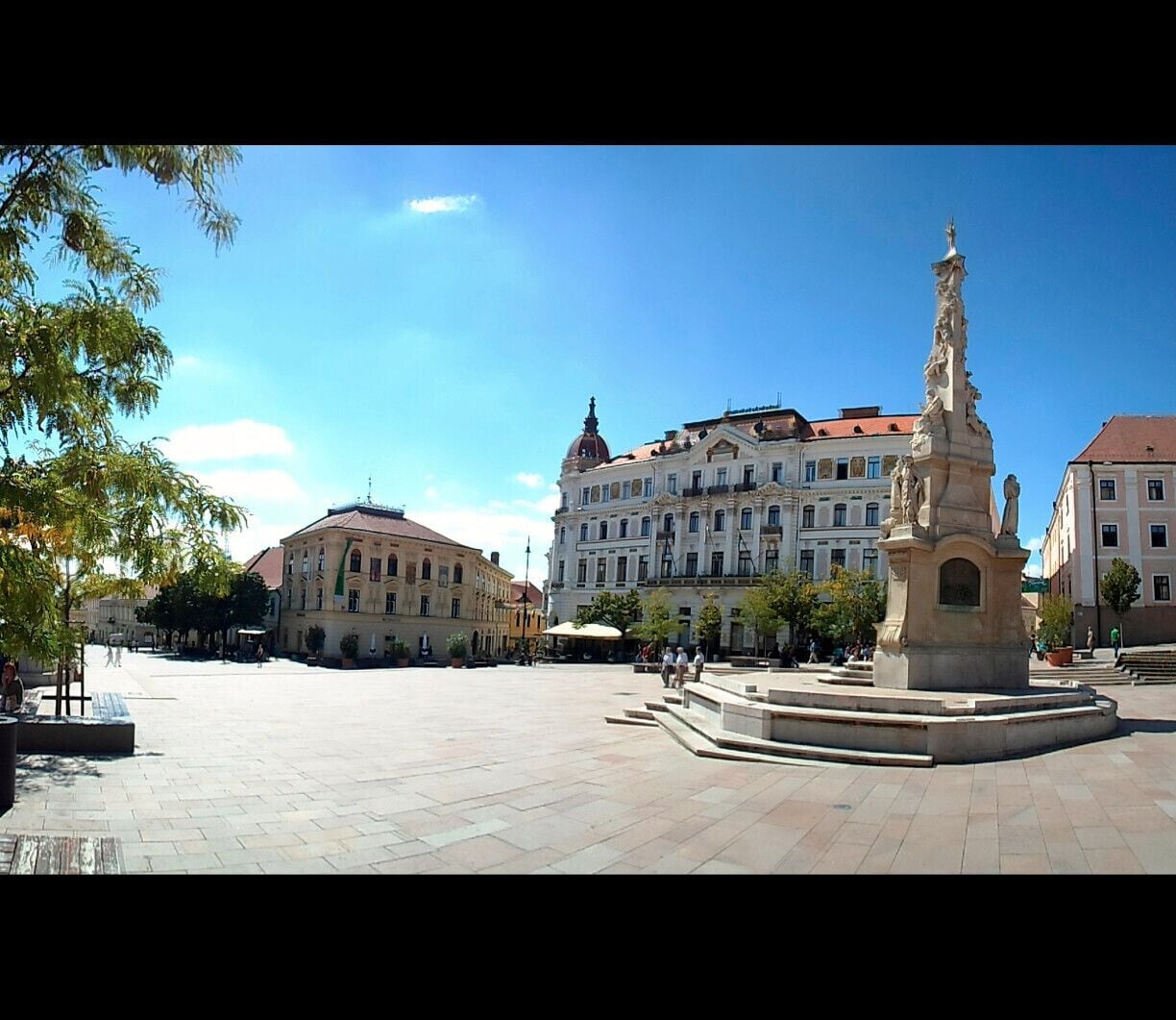 Una plaza con un monumento central, rodeada de edificios históricos.