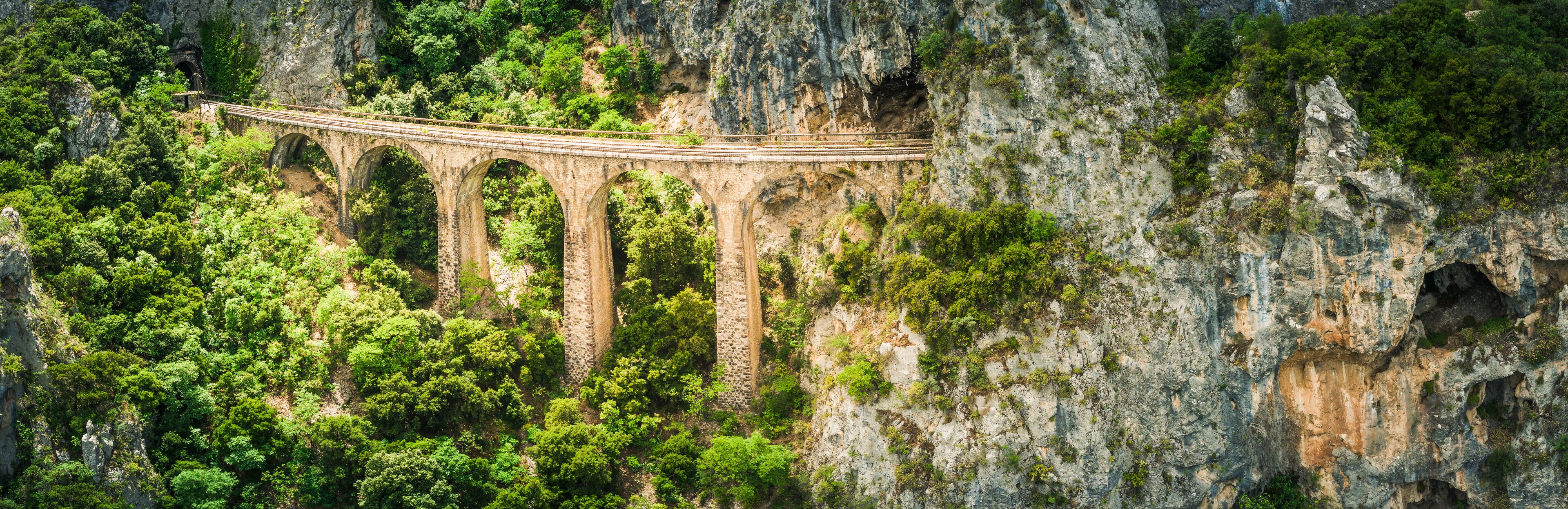 A stone bridge spanning a deep gorge with dense forest on either side.