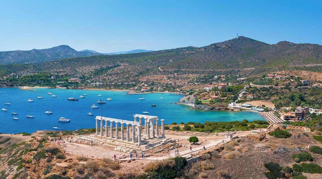 Panoramic view of the Temple of Poseidon at Cape Sounion at the edge of Attica, Greece, with moored sailboats in the bay during summer time