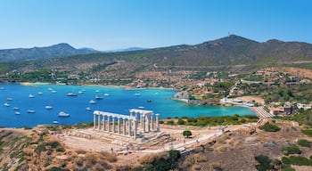 Panoramic view of the Temple of Poseidon at Cape Sounion at the edge of Attica, Greece, with moored sailboats in the bay during summer time