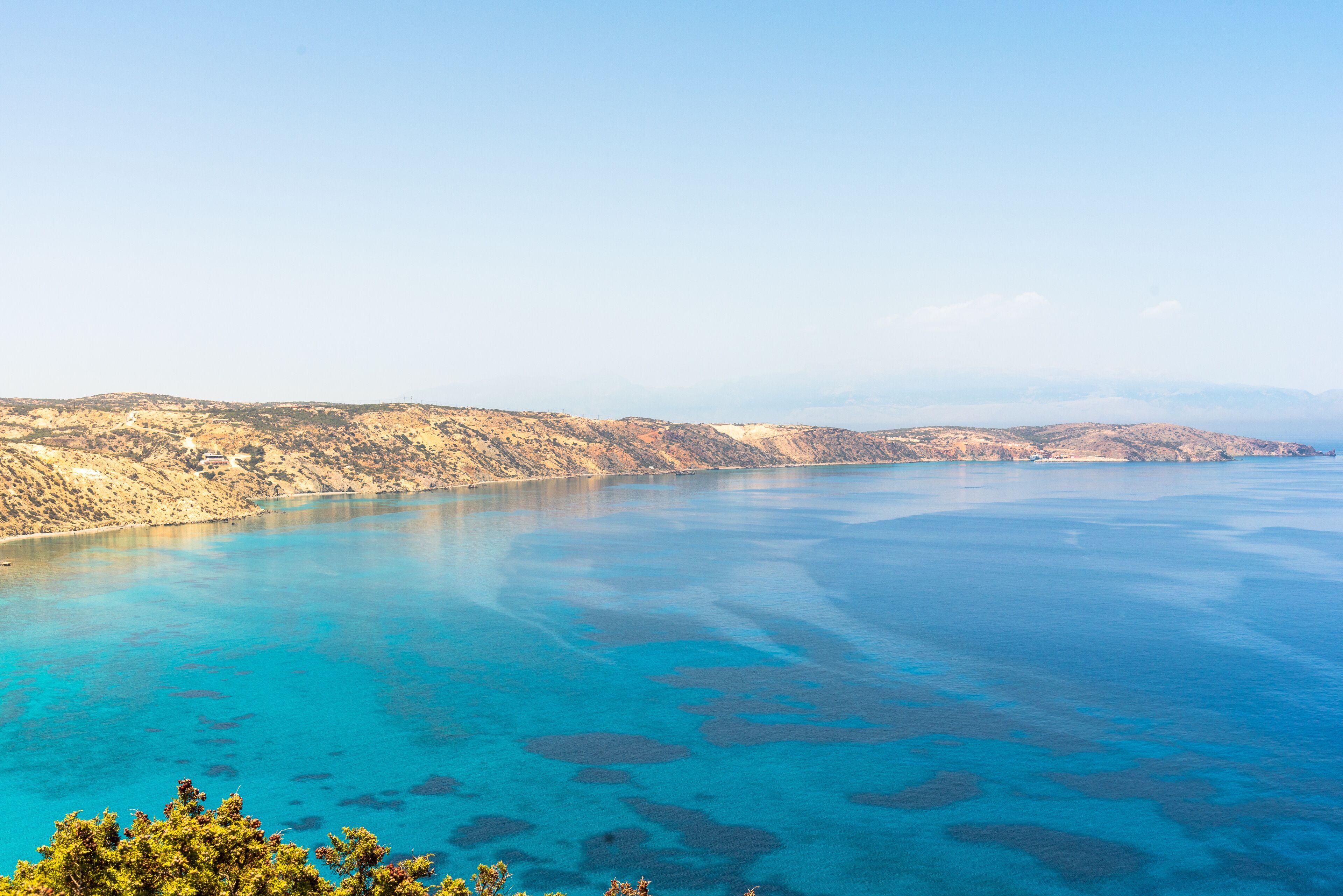 A coastal landscape with clear blue waters and rocky terrain.