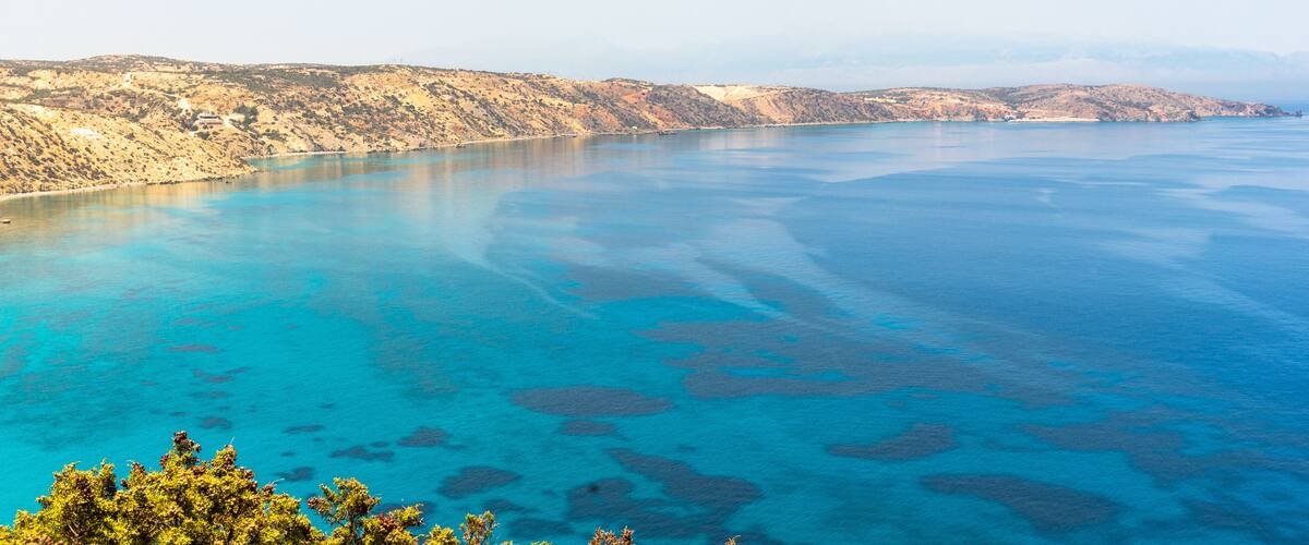 A coastal landscape with clear blue waters and rocky terrain.