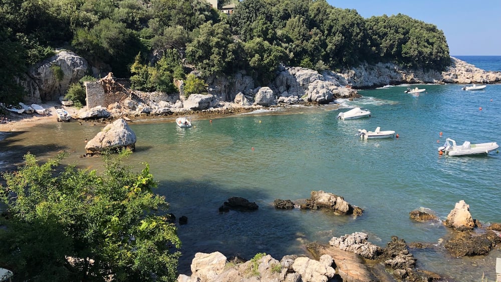 A coastal landscape with rocky shores, clear turquoise waters, and boats.