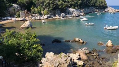 A coastal landscape with rocky shores, clear turquoise waters, and boats.