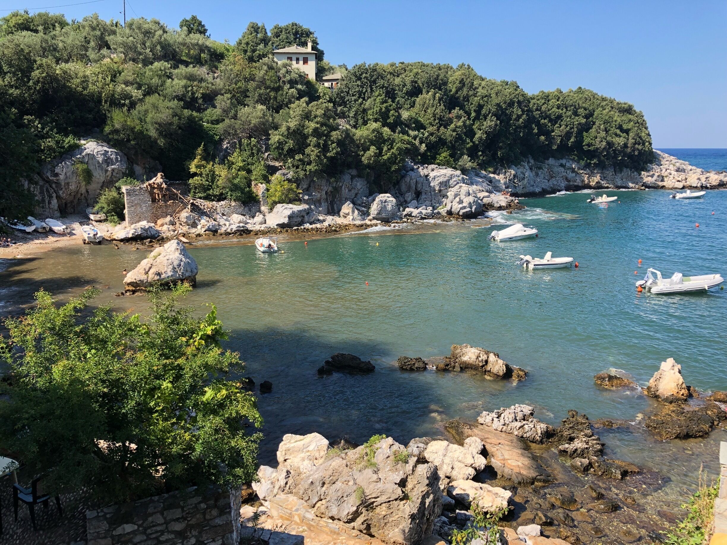 A coastal landscape with rocky shores, clear turquoise waters, and boats.