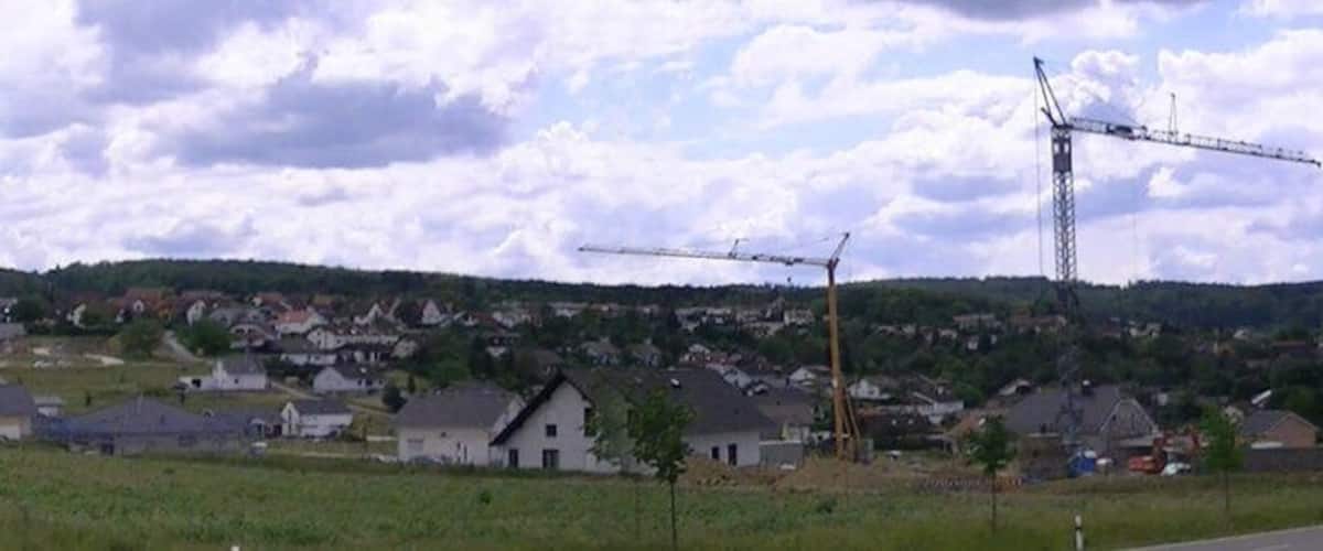 A rural landscape with a wind turbine, houses, and rolling hills.