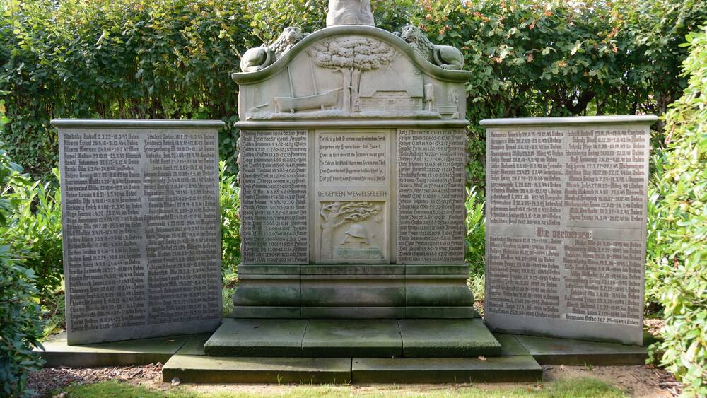 A stone monument with inscriptions, surrounded by greenery.