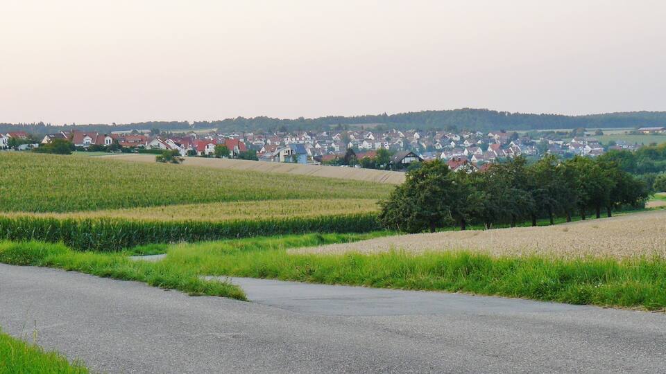 A rural landscape with fields, a road, and a village in the background.