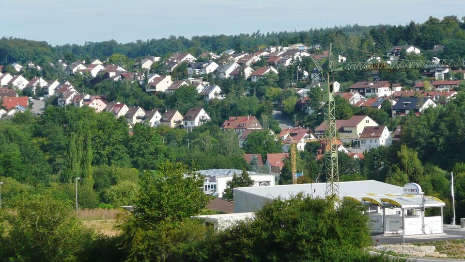 A residential area with houses on a hillside, a clean park, and a crane.