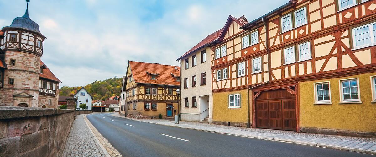 A cobblestone street lined with traditional half-timbered houses and a historic tower.