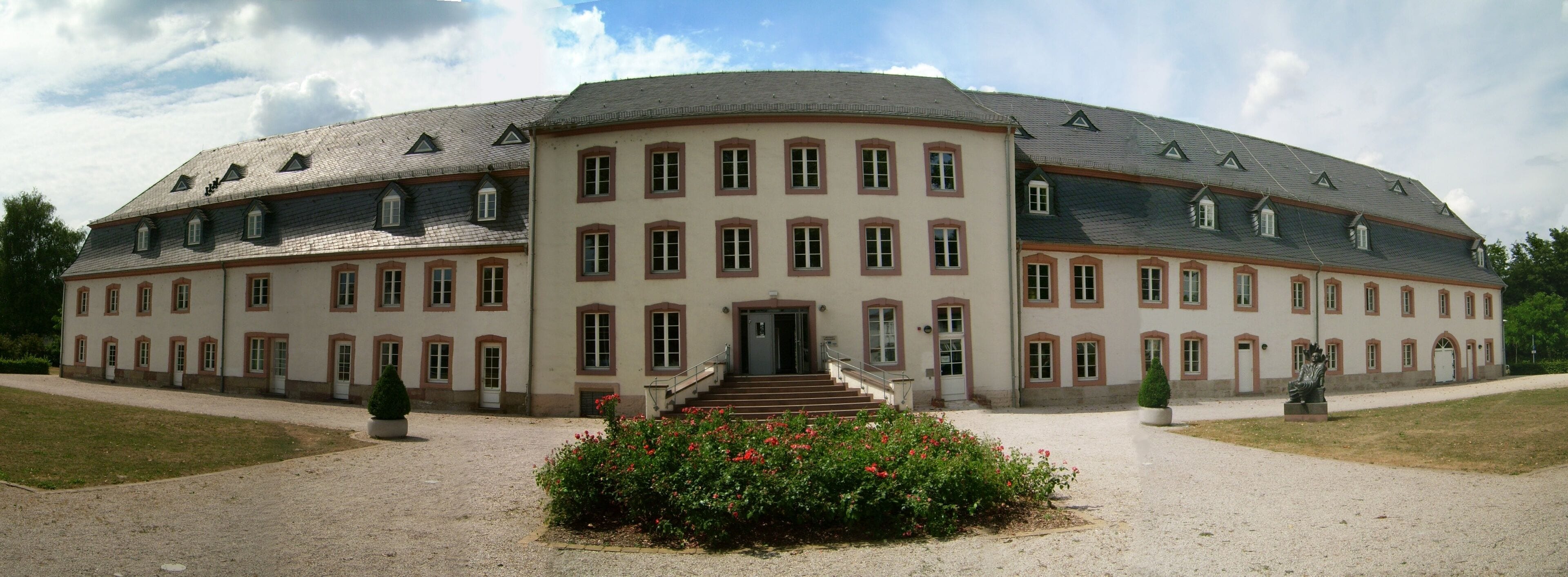 A large, historic building with a symmetrical facade, multiple windows, and a central entrance with steps.
