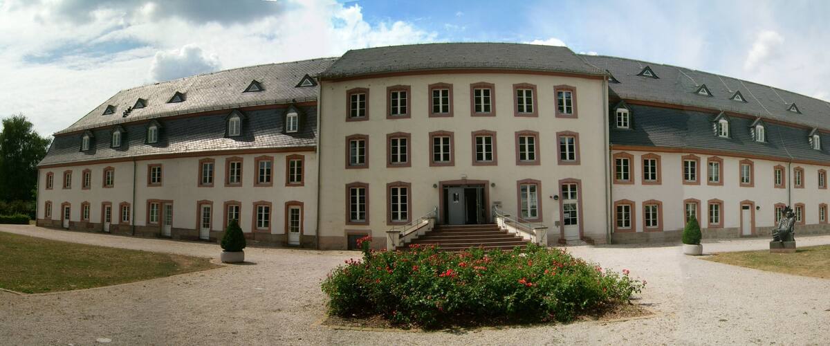 A large, historic building with a symmetrical facade, multiple windows, and a central entrance with steps.