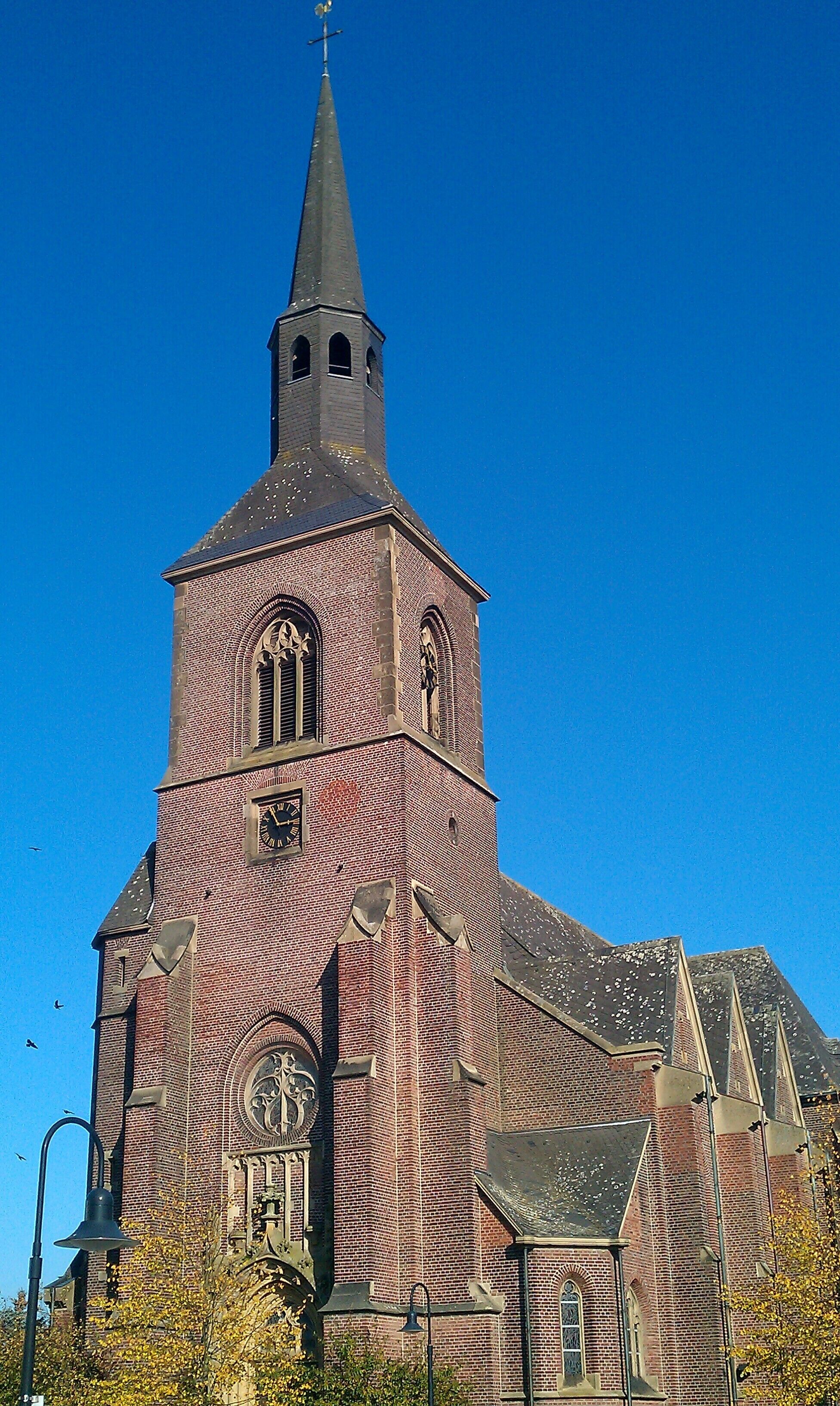 A large brick church with a tall steeple and a clock tower.